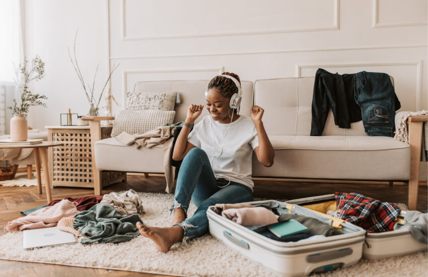 Femme avec casque d'écouteur joyeuse qui range son bagage