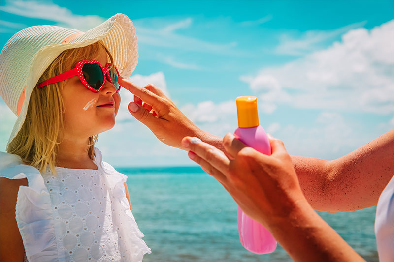 fillette sur la plage avec creme solaire